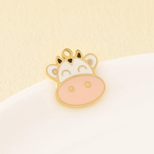 Close-up of cute pink and white cow enamel charm with gold plating for DIY jewelry making