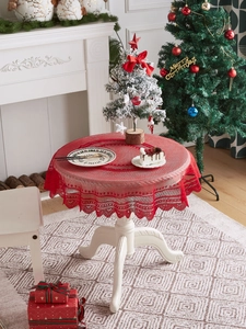 Detailed close-up of a festive red round tablecloth with lace edges on a small table