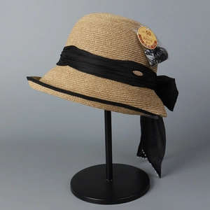 Detail of woven straw hat with black bow and delicate pearl edge trim for sun protection