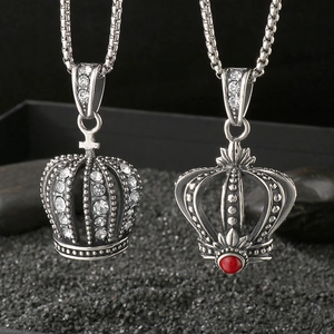 Retro punk crown pendants with crystals and red bead on black textured sand background