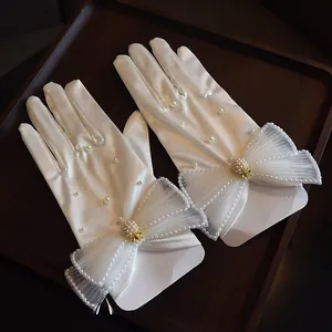 Detail of white satin bridal gloves with lace pearls and golden pineapple buckle decoration