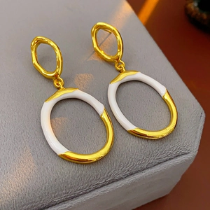 Detail of gold and white enamel irregular oval earrings on a velvet jewelry box display