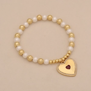 Detail of beaded bracelet with gold beads, white pearls, and red heart pendant with stones