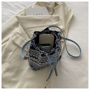 Top-down view of a woven blue and white bucket bag showing interior capacity and phone