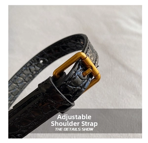 Detail of adjustable black crocodile embossed leather strap with vintage gold buckle