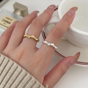 Close-up of gold and silver twisted rope rings on fingers with lifestyle background