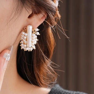 Gros plan de boucles d'oreilles géométriques dorées avec barre et perles blanches
