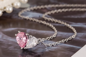 Macro shot of silver necklace with pink heart-shaped zircon pendant and pearl accents