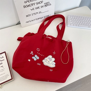 Detail of red canvas tote bag featuring cute bunny embroidery and drawstring closure