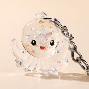 Macro detail of octopus acrylic keychain with white pearls and gold foil inside