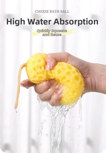 Macro shot of yellow cheese-shaped bath sponge being squeezed to show high water drainage
