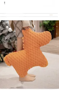 Detailed view of orange waffle texture on a dinosaur plush pillow in a cozy home setting
