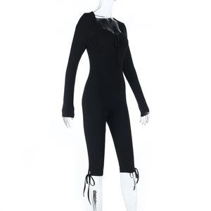 Detail view of black ribbed knit jumpsuit featuring lace-up collar and tight-fit sleeve cuffs