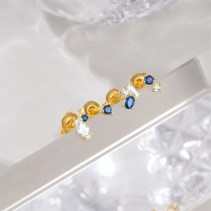 Macro shot of 925 silver gold-plated stud earrings with blue and clear gemstones