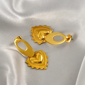 Vue détaillée des boucles d'oreilles cœur doré avec texture rayonnante sur satin