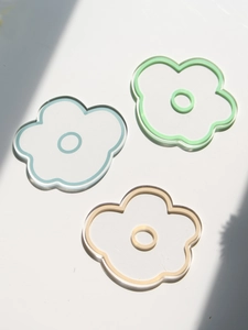 Detail of flower shaped acrylic coasters in blue green and beige with sun shadows