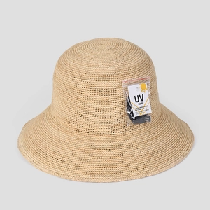 Detailed close-up of natural beige raffia sun hat texture with UV care label
