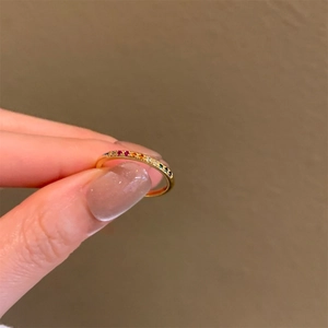 Dettaglio dell'anello dorato minimalista con zirconi colorati a gradiente arcobaleno
