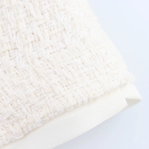 Close-up of cream tweed woven fabric texture with smooth trim on elegant women suit