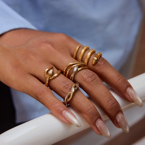 Detail of model wearing gold and silver snake rings with emerald zircon and pearl inlay