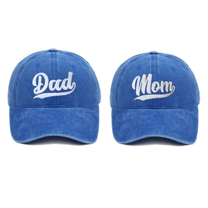 Detail of Mom and Dad cursive embroidery on two washed cotton baseball caps in denim blue