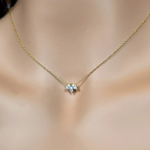 Macro detail of a gold clover necklace featuring three marquise-cut zircon stones on a chain