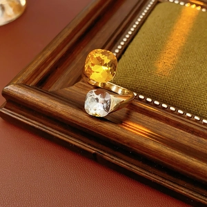 Detail of dual crystal open ring with yellow and clear square gems on gold band