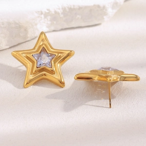 Detail view of 18K gold plated star stud earrings with clear zircon on stone background