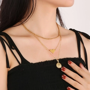 Dettaglio collana dorata a strati con cuore e ciondolo occhio inciso su modella