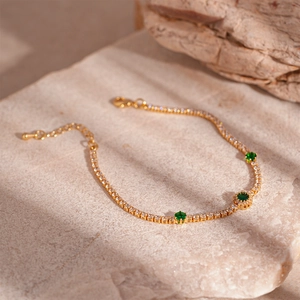 Detail of vintage emerald zircon gold bracelet on natural stone with soft outdoor lighting