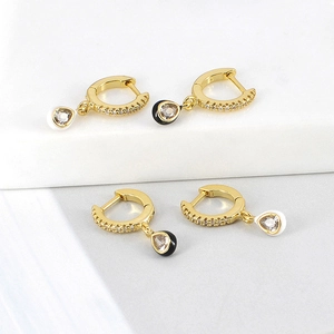 Detailed view of gold hoop earrings with black and white zircon teardrop pendants