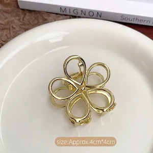 Detail of a 4cm gold plum blossom metal hair claw clip with spring on a white plate