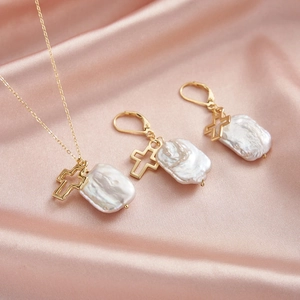 Baroque pearl jewelry set with gold cross pendants on elegant pink silk background
