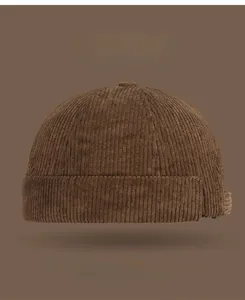 Detail showing the brown corduroy fabric texture and ribbed pattern of the brimless cap