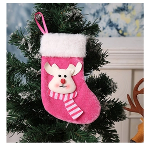 Botte de Noël rose avec renne en peluche suspendue au sapin près d'une cheminée