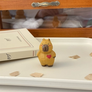 Detail of hand-carved wooden capybara figurine with red heart and warm wood texture