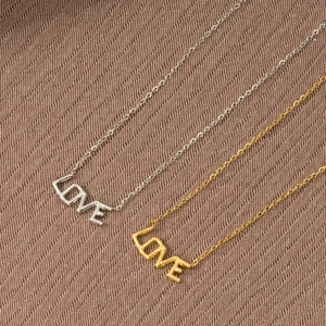 Dettaglio dei ciondoli con scritte LOVE in oro e argento su tessuto strutturato