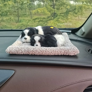 Detailed view of realistic black and white plush dogs on a beige mat on car dashboard