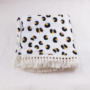 Detail of white double-layer muslin baby blanket with leopard print and tassel trim