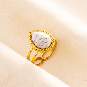 Detail of gold double-layer ring with teardrop marble stone on beige silk fabric