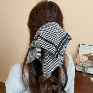 Elegant black and white checkered fabric hair scrunchie shown on model in a cozy setting