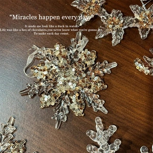Acrylic Christmas snowflake hanging ornament with gold sequins on dark wood background