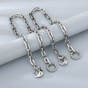 Macro view of four silver punk trouser chains with skull hook clasps on a fabric background