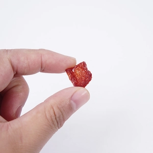 Realistic miniature PVC smoked meat model held between fingers for scale with white background