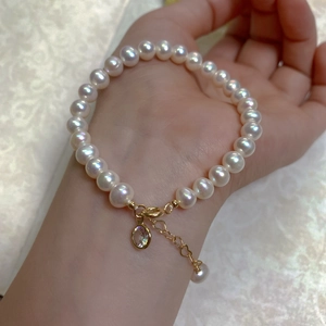 Close-up of baroque pearl bracelet with heart-shaped gold chain and crystal charm