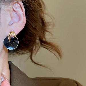 Nahaufnahme der geometrischen Gold-Schwarz Emaille-Ohrstecker für elegantes Tages-Styling