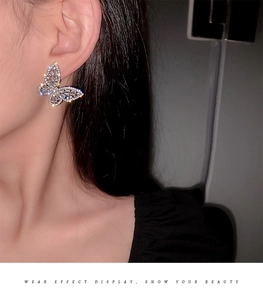 Close-up of sparkling silver butterfly stud earring with tiny zircons on model ear