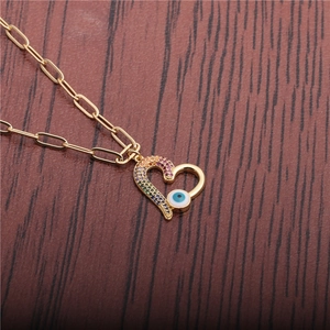 Golden heart necklace with evil eye and colorful zircon stones on dark wood