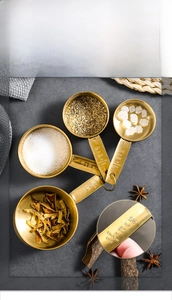 Macro shot of four champagne gold stainless steel measuring cups with engraved capacity marks