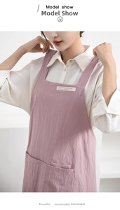 Close-up of pink linen apron with cross-back straps, large front pocket and textile label
